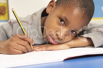 Unhappy Schoolboy Studying In Classroom