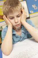 Stressed Schoolboy Studying In Classroom