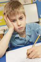 Stressed Schoolboy Studying In Classroom