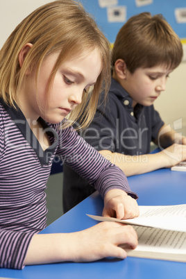Schoolgirl Reading Book In Classroom