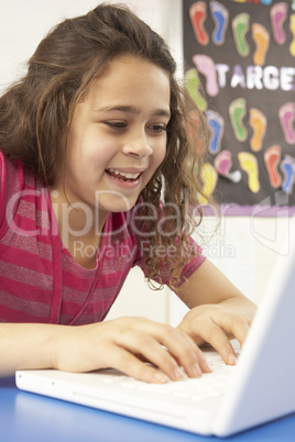 Schoolgirl In IT Class Using Computer With Teacher