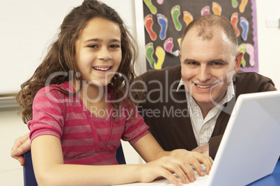 Schoolgirl In IT Class Using Computer With Teacher