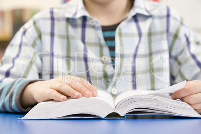 Close Up Of Schoolboy Studying Textbook In Classroom