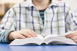 Close Up Of Schoolboy Studying Textbook In Classroom
