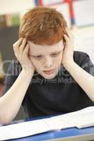 Stressed Schoolboy Studying In Classroom