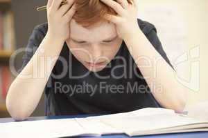 Stressed Schoolboy Studying In Classroom