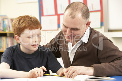 Male Pupil Studying in classroom with teacher