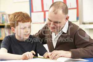 Male Pupil Studying in classroom with teacher