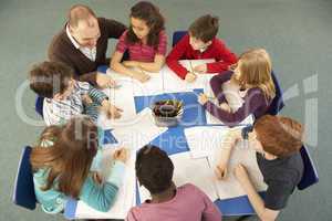 Overhead View Of Schoolchildren Working Together At Desk With Te