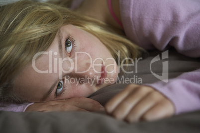 Depressed Teenage Girl Lying In Bedroom