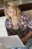 Guilty Looking Teenage Girl Using Laptop At Home