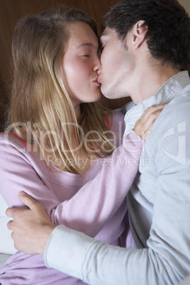 Romantic Teenage Couple Kissing On Sofa At Home Together