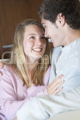 Romantic Teenage Couple Sitting On Sofa At Home Together