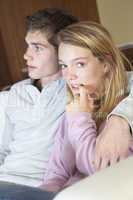 Nervous Looking Teenage Girl Sitting On Sofa At Home With Boyfri