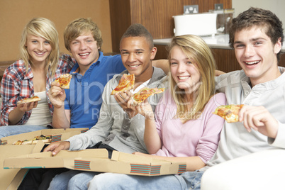 Group Of Teenage Friends Sitting On Sofa At Home Eating Pizza