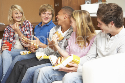 Group Of Teenage Friends Sitting On Sofa At Home Eating Fast Foo
