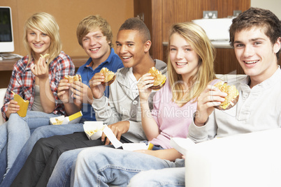 Group Of Teenage Friends Sitting On Sofa At Home Eating Fast Foo