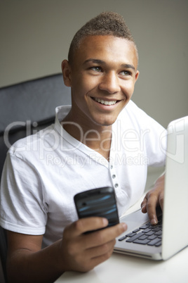 Teenage Boy Using Laptop And Mobile At Home