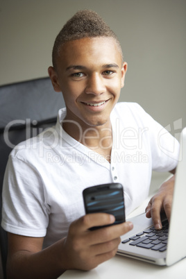 Teenage Boy Using Laptop And Mobile At Home