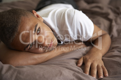 Depressed Teenage Boy Lying In Bedroom