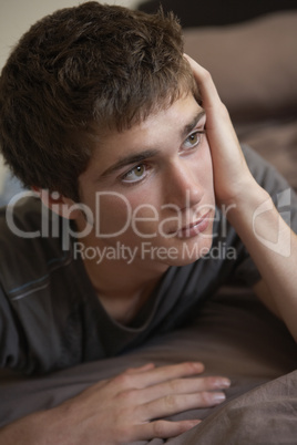 Depressed Teenage Boy Lying In Bedroom