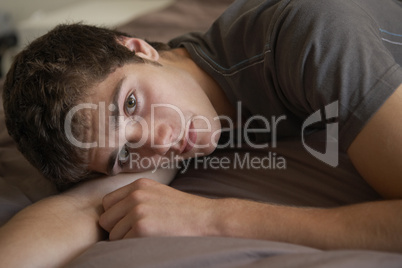 Depressed Teenage Boy Lying In Bedroom