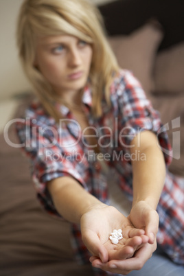 Depressed Teenage Girl Sitting In Bedroom With Pills