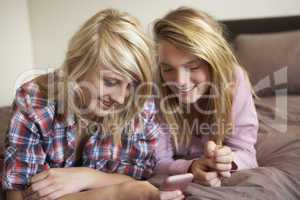 Two Teenage Girls Lying On Bed Looking At Pregnancy Testing Kit