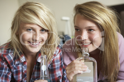 Two Teenage Girls Sitting On Sofa At Home Drinking Alcohol
