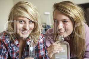 Two Teenage Girls Sitting On Sofa At Home Drinking Alcohol