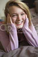 Happy Teenage Girl Sitting In Bedroom