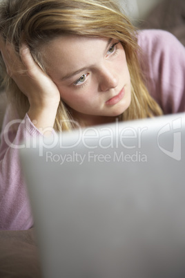 Unhappy Teenage Girl Using Laptop At Home