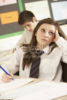 Bored Female Teenage Student Studying In Classroom