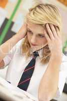 Stressed Female Teenage Student Studying In Classroom