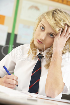 Stressed Female Teenage Student Studying In Classroom