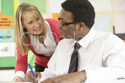 Teenage Student Working In Classroom With Teacher