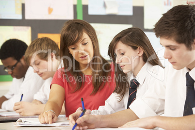 Teenage Students Studying In Classroom With Teacher