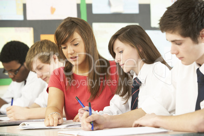 Teenage Students Studying In Classroom With Teacher