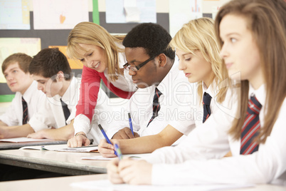 Teenage Students Studying In Classroom With Teacher