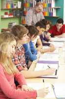 Teenage Students Studying In Classroom With Tutor