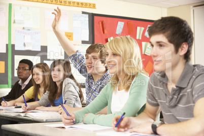Teenage Students Studying In Classroom Answering Question