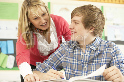 Male Teenage Student Studying In Classroom With Teacher