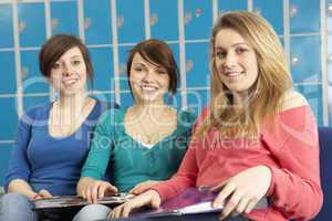 Female Teenage Students Relaxing By Lockers In School
