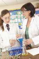 Female Teenage Student And Tutor In Science Class With Experimen
