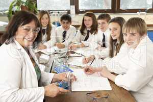 Group Of Teenage Students In Science Class With Tutor