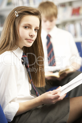 Female Teenage Student In Library Reading Book