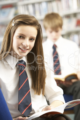 Female Teenage Student In Library Reading Book