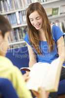 Female Teenage Student In Library Reading Book