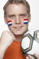 Young Male Football Fan With Dutch Flag Painted On Face