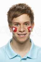 Young Male Sports Fan With Swiss Flag Painted On Face